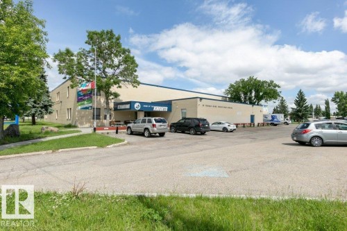 Expansive building with a light-colored facade and a large parking area - 323 16807 100 Avenue, Edmonton, AB - Outdoor