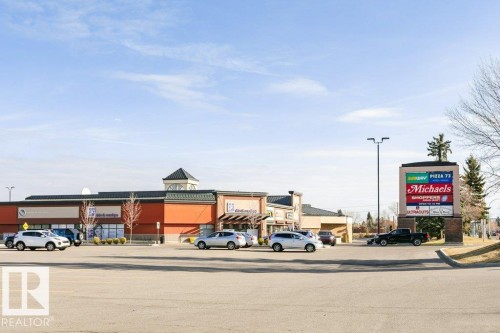 Commercial retail complex featuring a prominent tenant sign, extensive paved parking, and multiple storefronts - 323 16807 100 Avenue, Edmonton, AB - Outdoor