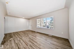 Spacious room featuring wood-finish flooring, white baseboards, and neutral wall tones - 
