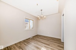 Room featuring wood-finish flooring, a window with exterior brick exposure, and a decorative chandelier with clear glass shades - 