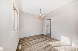Bright room featuring wood-finish flooring, a contemporary ceiling fixture, white baseboards, and a large window with white trim - 