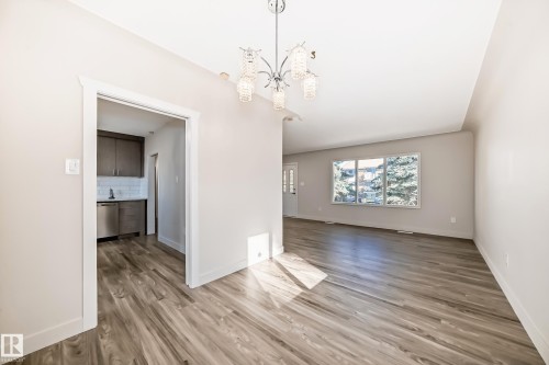 Spacious interior featuring wood-finish flooring, a contemporary chandelier, and light-toned walls - 13124 83 Street, Edmonton, AB - Indoor Photo Showing Other Room