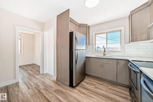 Contemporary kitchen featuring wood-finish flooring, light wood-grain cabinetry, stainless steel appliances, white subway tile backsplash, and light-toned countertops - 13124 83 Street, Edmonton, AB - Indoor Photo Showing Kitchen
