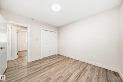 Room featuring wood-finish flooring, white walls, and a flush-mount ceiling light - 