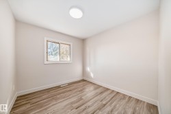 Spacious room with wood-finish flooring, neutral wall tones, and a bright window for natural light - 