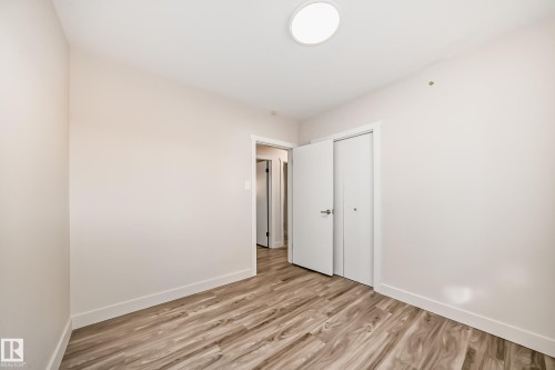Room featuring wood-finish flooring, light-toned walls, white trim, and a flush-mount ceiling light fixture - 13124 83 Street, Edmonton, AB - Indoor Photo Showing Other Room