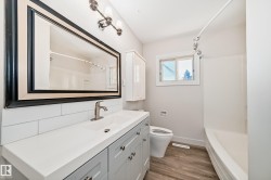 Bathroom featuring a vanity with an integrated sink, a large framed mirror, white subway tile backsplash, and a shower-over-tub combination - 