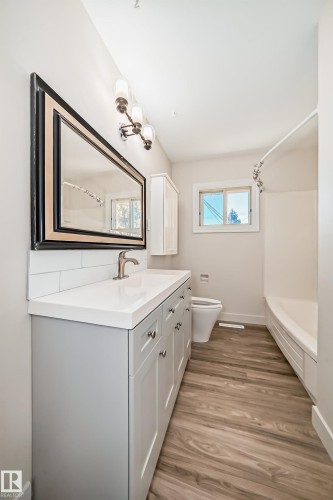 Bathroom featuring a light gray vanity with brushed nickel hardware, white countertop, and subway tile backsplash - 13124 83 Street, Edmonton, AB - Indoor Photo Showing Bathroom