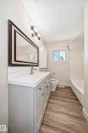 Bathroom featuring a light gray vanity with brushed nickel hardware, white countertop, and subway tile backsplash - 