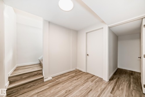 Interior space featuring wood-finish flooring, white walls, and a contemporary flush-mount ceiling light - 13124 83 Street, Edmonton, AB - Indoor Photo Showing Other Room