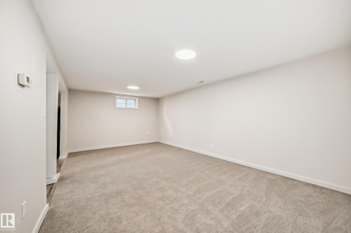 Spacious room featuring neutral carpeting, light-toned walls, recessed ceiling lighting, and a window providing natural illumination - 13124 83 Street, Edmonton, AB - Indoor
