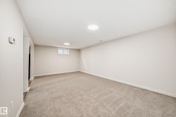 Spacious room featuring neutral carpeting, light-toned walls, recessed ceiling lighting, and a window providing natural illumination - 