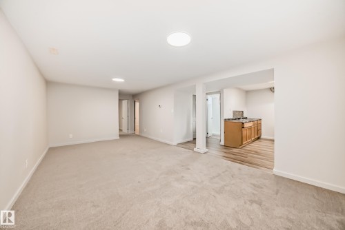 Spacious room featuring neutral carpeting, recessed lighting, and a separate area with wood-finish flooring, wood cabinetry, and a countertop - 13124 83 Street, Edmonton, AB - Indoor
