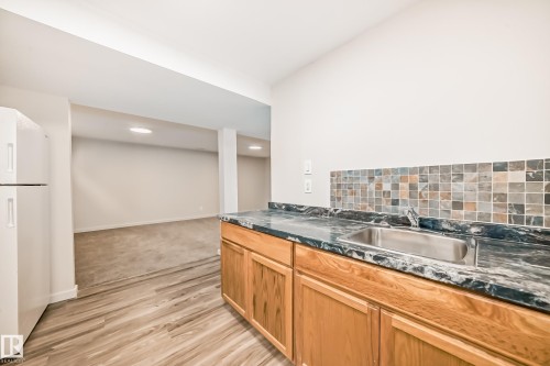 Kitchenette featuring a stainless steel sink, wood cabinetry, and a mosaic tile backsplash - 13124 83 Street, Edmonton, AB - Indoor Photo Showing Kitchen