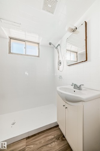 Bathroom featuring a walk-in shower with white tile surround, a built-in window, and a white vanity with an integrated sink - 13124 83 Street, Edmonton, AB - Indoor Photo Showing Bathroom