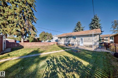 Expansive backyard featuring a green lawn, wood fence, and mature evergreen trees - 13124 83 Street, Edmonton, AB - Outdoor
