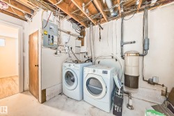 Laundry area featuring a side-by-side washer and dryer, exposed ceiling joists, electrical panel, and utility piping - 