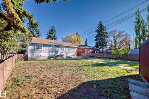Spacious backyard featuring a section of manicured lawn, a concrete patio, and a brown wooden fence enclosing the perimeter - 13124 83 Street, Edmonton, AB - Outdoor