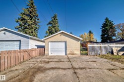 Detached garage with a white panel door, stucco exterior, and gable roof - 
