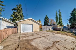 Detached garage with a paneled door, stucco exterior, and a fenced perimeter - 