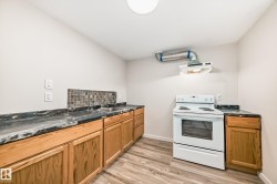 Functional kitchen space featuring wood cabinetry, dark patterned countertops, a mosaic tile backsplash, wood-finish flooring, and a white electric range with an overhead exhaust hood - 