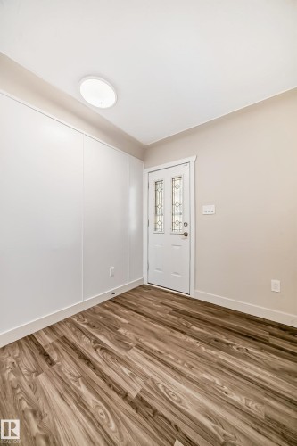 Entryway featuring wood-finish flooring, a white paneled accent wall, and a frosted glass door - 13124 83 Street, Edmonton, AB - Indoor Photo Showing Other Room