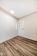 Entryway featuring wood-finish flooring, a white paneled accent wall, and a frosted glass door - 