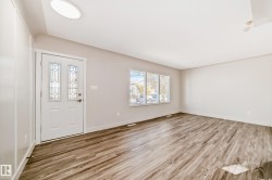 Entry area featuring a white door with decorative glass inserts, wood-finish flooring, and light-toned walls - 