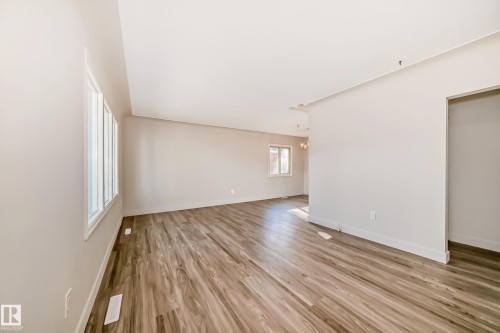 Spacious interior featuring wood-finish flooring, neutral wall tones, and multiple windows for natural light - 13124 83 Street, Edmonton, AB - Indoor Photo Showing Other Room