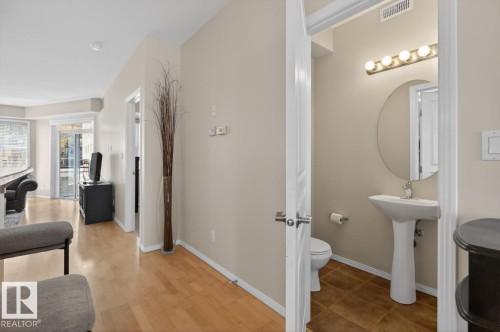 Powder room featuring a pedestal sink, round mirror, and tile flooring - 614 10503 98 Avenue, Edmonton, AB - Indoor