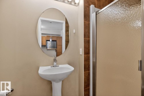Bathroom featuring a pedestal sink, oval mirror, and a shower with a textured glass door - 614 10503 98 Avenue, Edmonton, AB - Indoor Photo Showing Bathroom