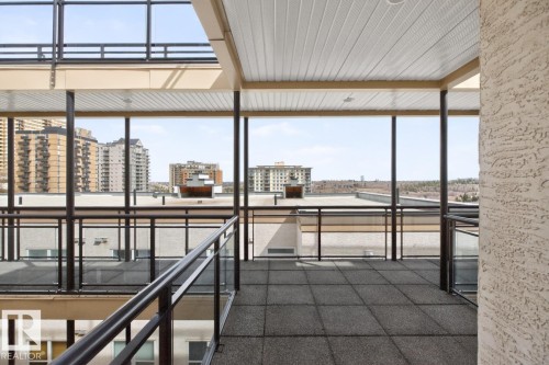 Expansive outdoor corridor featuring a covered patio with square tile flooring, glass panel railings, and metal framing - 614 10503 98 Avenue, Edmonton, AB - Indoor Photo Showing Other Room