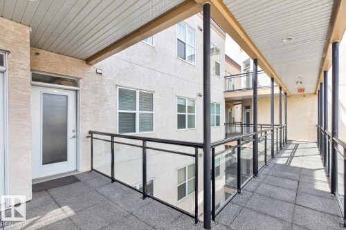 Exterior walkway with textured wall facade, white entry door with frosted glass panel, and dark gray floor tiles - 614 10503 98 Avenue, Edmonton, AB - Outdoor With Exterior