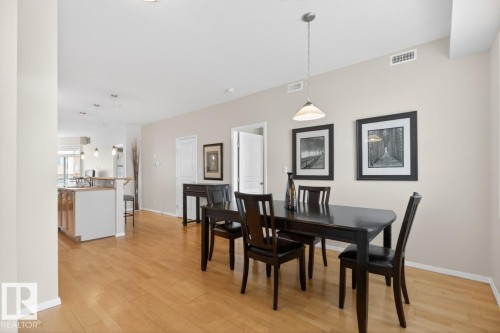 Open concept living area featuring wood-finish flooring throughout, a dining space with pendant lighting, and a kitchen island with a wood countertop - 614 10503 98 Avenue, Edmonton, AB - Indoor Photo Showing Dining Room
