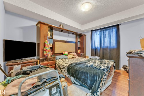 Bedroom featuring wood-finish flooring, light blue painted walls, and a window with dark drapes - 101 10136 160 Street Nw, Edmonton, AB - Indoor Photo Showing Bedroom