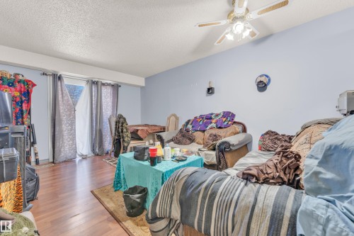 Living area featuring wood-finish flooring, light blue wall paint, and a ceiling fan with integrated lighting - 101 10136 160 Street Nw, Edmonton, AB - Indoor