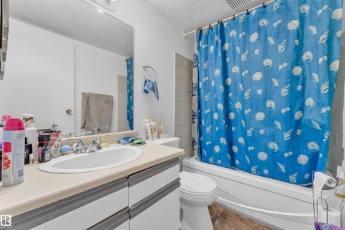 Bathroom featuring a white integrated sink, light-toned countertop, and a built-in vanity with cabinetry - 101 10136 160 Street Nw, Edmonton, AB - Indoor Photo Showing Bathroom