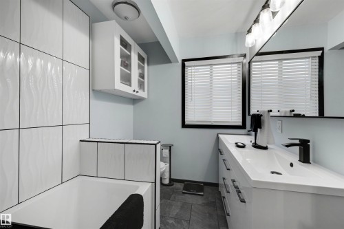 Modern bathroom featuring a built-in tub with textured white wall tiling - 9602 85 Street, Edmonton, AB - Indoor