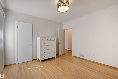 Hardwood flooring enhances this room featuring neutral wall tones, a contemporary ceiling light fixture, and white trim - 9602 85 Street, Edmonton, AB - Indoor