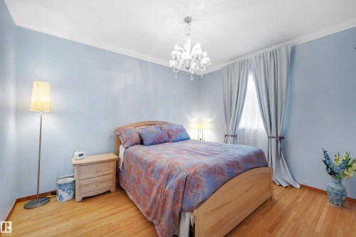 Room featuring light wood-finish flooring, a crystal chandelier, and light blue wall paint - 9602 85 Street, Edmonton, AB - Indoor Photo Showing Bedroom
