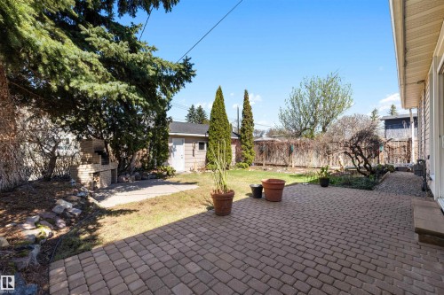 Expansive brick paver patio with a stone outdoor fireplace - 9602 85 Street, Edmonton, AB - Outdoor
