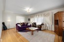 Living area featuring light wood-finish flooring, an arched doorway, a decorative ceiling fixture, and a large window with draped window treatments - 9602 85 Street, Edmonton, AB  - Indoor Photo Showing Living Room 