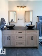 Dual vessel sinks with dark finish atop a dark countertop - 