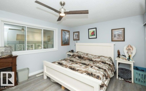 Bedroom featuring light gray wood-finish flooring, a white paneled headboard, and a white-framed sliding window - 27132A Twp Rd 632, Rural Westlock County, AB - Indoor Photo Showing Bedroom