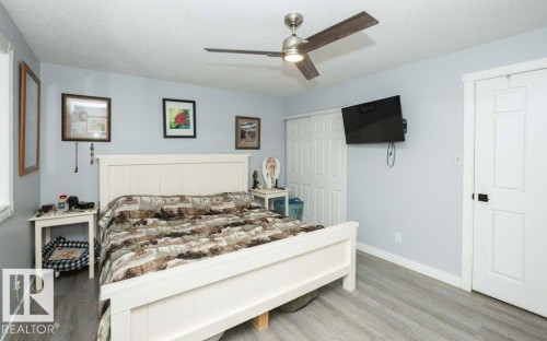Expansive room featuring wood-finish flooring, a contemporary ceiling fan with integrated lighting, and light blue wall tones - 27132A Twp Rd 632, Rural Westlock County, AB - Indoor Photo Showing Bedroom