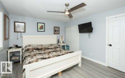 Expansive room featuring wood-finish flooring, a contemporary ceiling fan with integrated lighting, and light blue wall tones - 