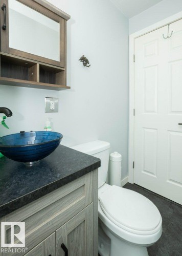 Powder room featuring a wood-finish vanity with a dark countertop and vessel sink - 27132A Twp Rd 632, Rural Westlock County, AB - Indoor Photo Showing Bathroom