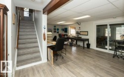 Spacious lower-level room featuring wood-finish flooring, a drop ceiling with recessed lighting, and white walls - 