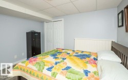 Bedroom featuring light blue walls, wood-finish flooring, and a white drop-panel ceiling - 