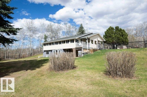 Exterior residence featuring light-colored siding, a covered porch, and a second-story balcony - 27132A Twp Rd 632, Rural Westlock County, AB - Outdoor With Deck Patio Veranda